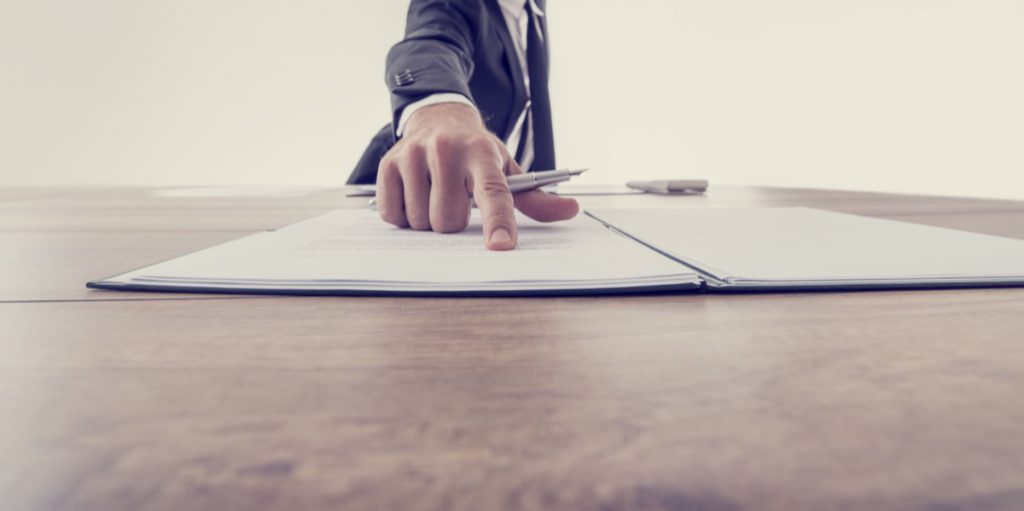 Front view of employer pointing to a contract where to sign, vintage effect toned image.