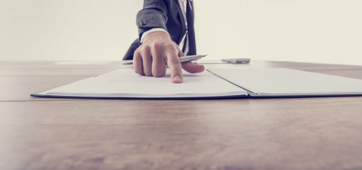 Front view of employer pointing to a contract where to sign, vintage effect toned image.