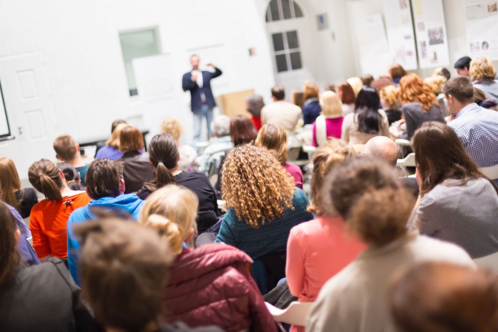 Speaker Giving a Talk at Business Meeting. Audience in the conference hall. Business and Entrepreneurship. Copy space on white board.