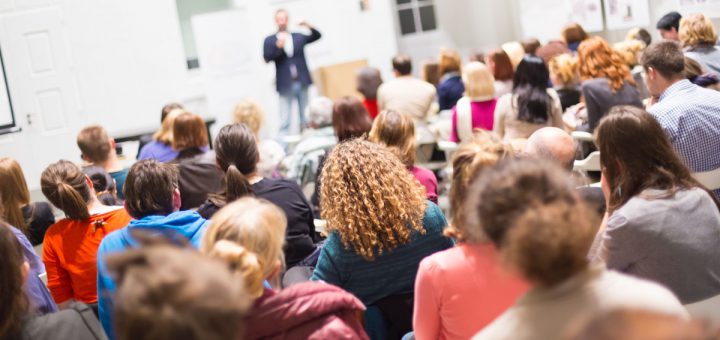 Speaker Giving a Talk at Business Meeting. Audience in the conference hall. Business and Entrepreneurship. Copy space on white board.