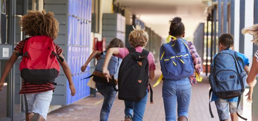 School kids running in elementary school hallway, back view