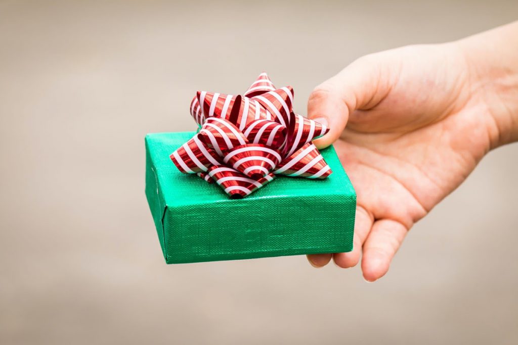 Woman hand hold a green gift box tied with red ribbon for give in the public park, present for Christmas and new year and valentine day or Important occasions concept.