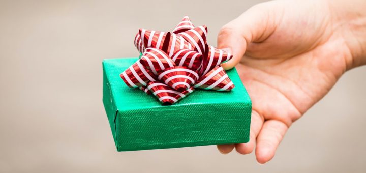 Woman hand hold a green gift box tied with red ribbon for give in the public park, present for Christmas and new year and valentine day or Important occasions concept.