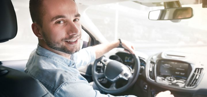 Young male driver behind the wheel. Sharing economy service or taxi driver concept