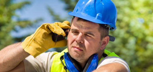 Tired worker with walkie talkie and safety equipment on oil plant
