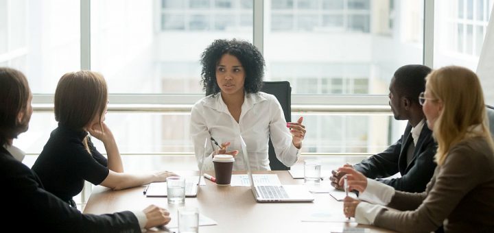 Black female boss leading corporate multiracial team meeting talking to diverse businesspeople, african american woman executive discussing project plan at group multi-ethnic briefing in boardroom