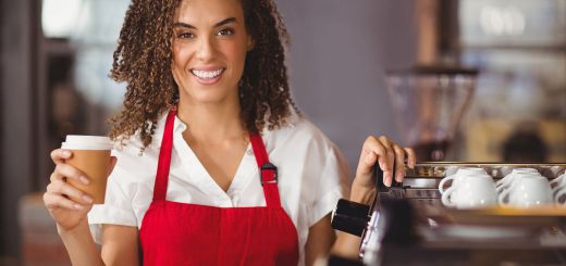Portrait of a waitress holding a take-away mug at the coffee shop