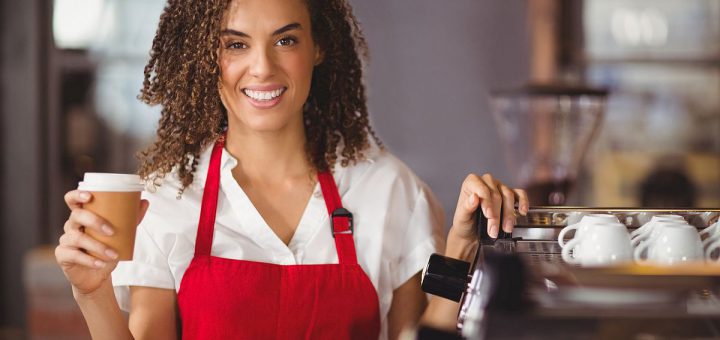 Portrait of a waitress holding a take-away mug at the coffee shop