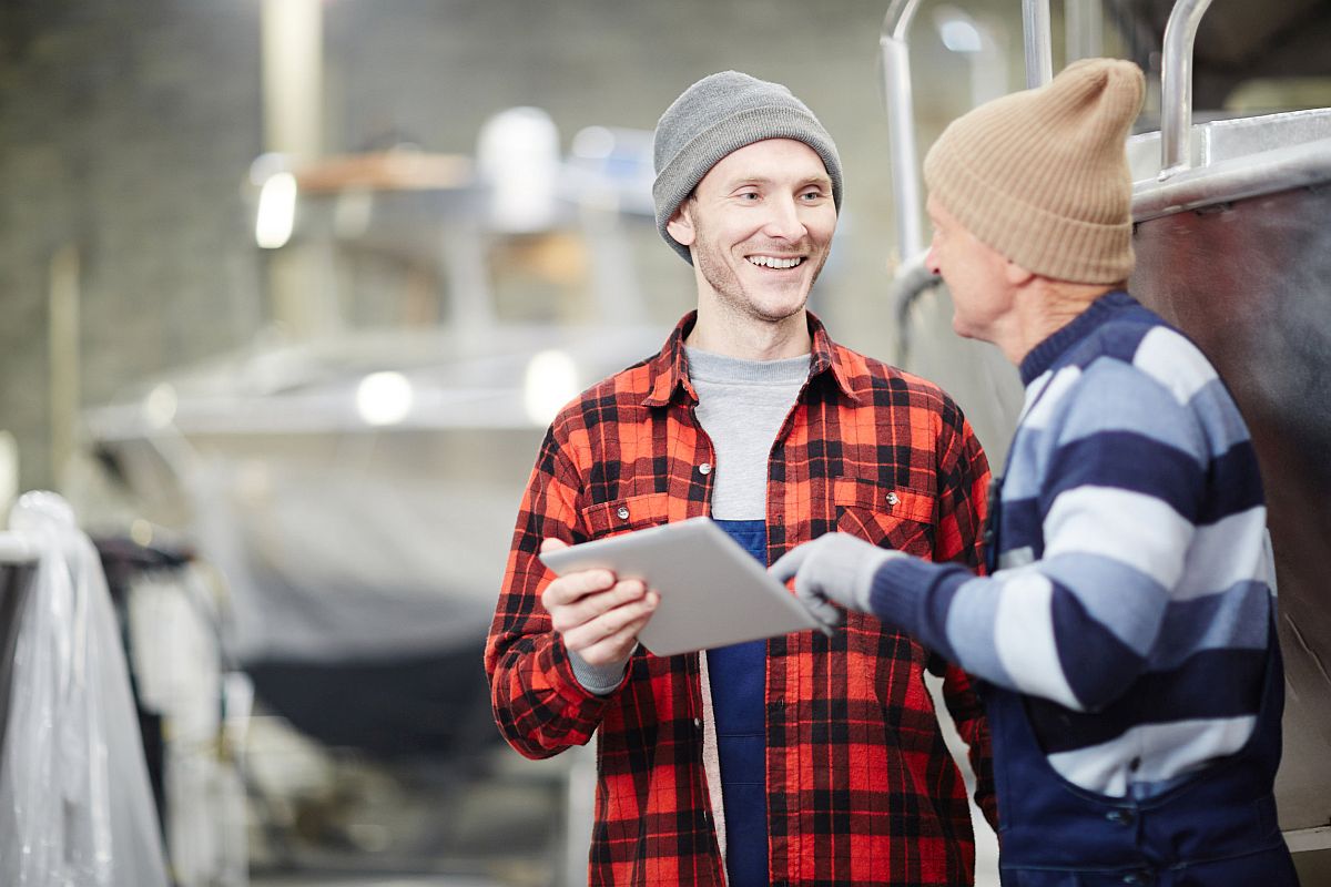 Young engineer listening to what his senior colleague is saying while pointing at touchpad display; forming a union organizing committee concept