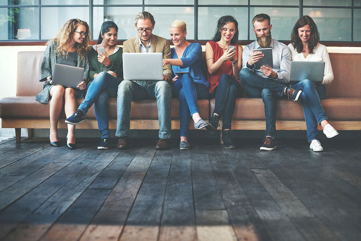 row of workers sharing laptops; communication and digital tools concept