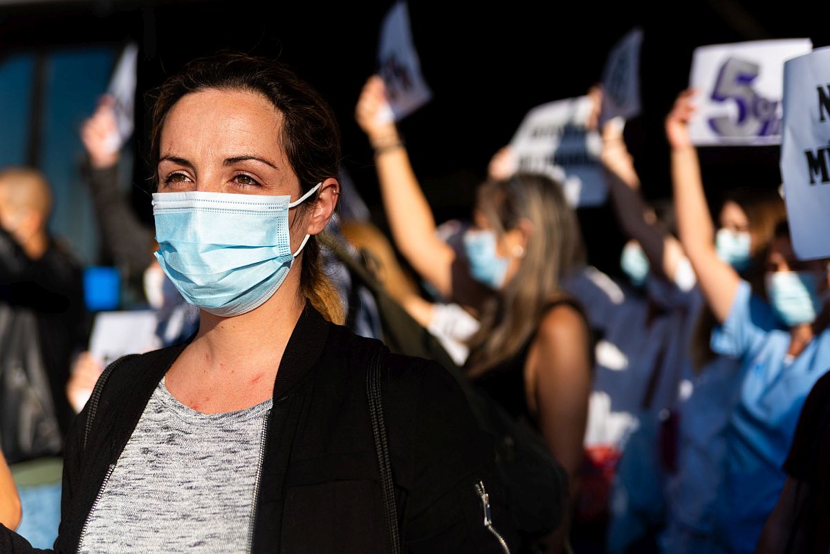 Woman in a surgical mask at a protest -- US labor strikes 2021 concept
