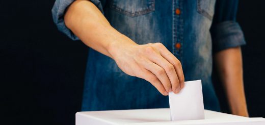 Front view of person holding ballot paper casting vote at a polling station for election vote in black background