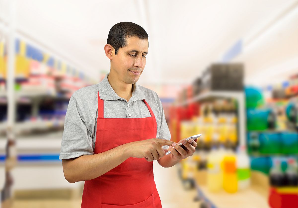worker uses smartphone at the supermarket; digital union-busting concept