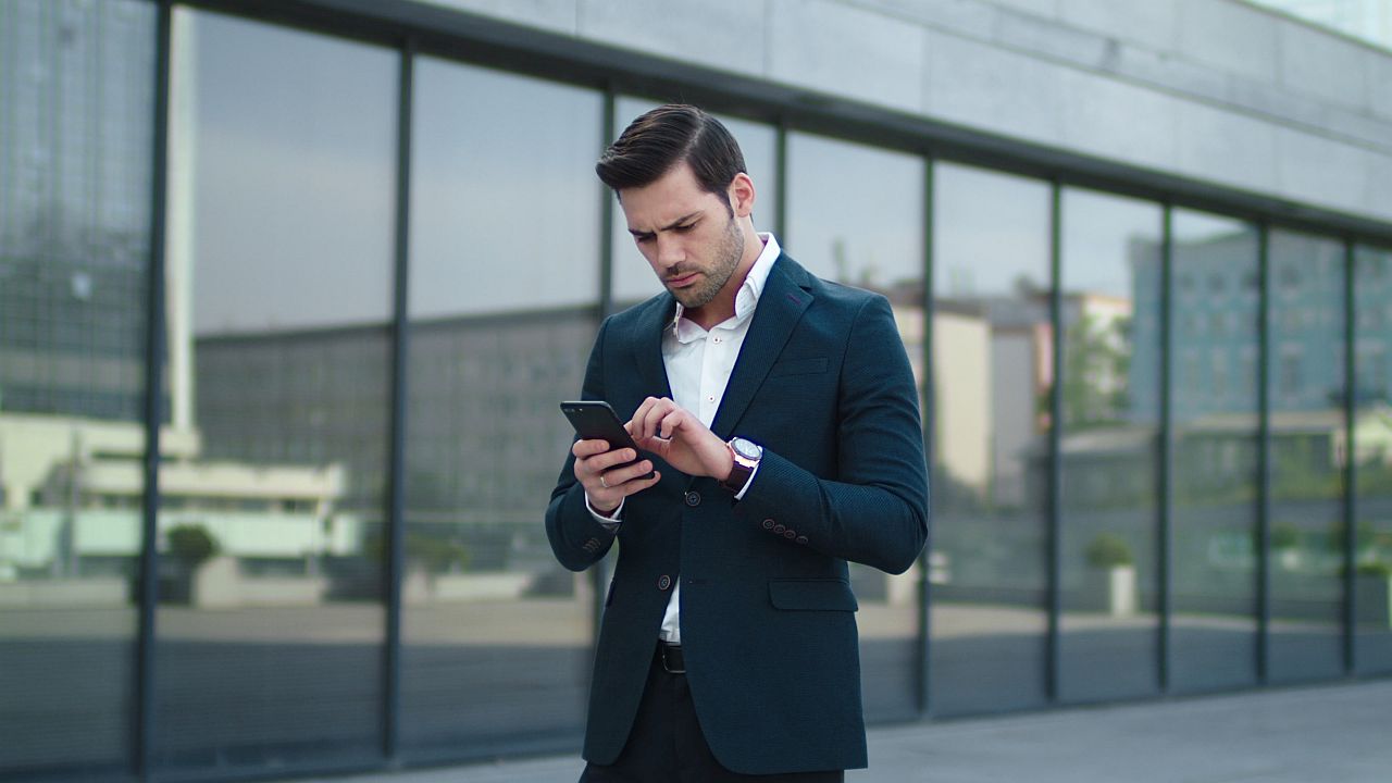 Disappointed man using smartphone outside; informal online spaces concept