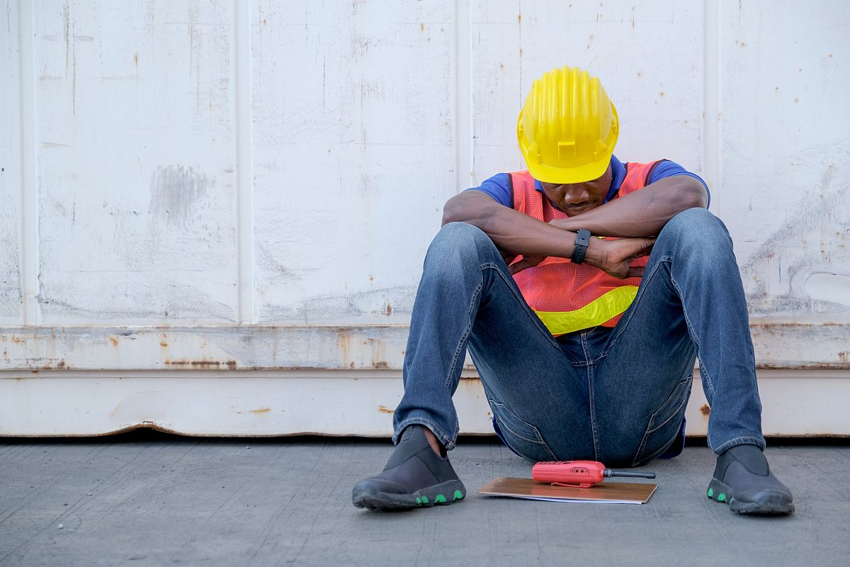 factory worker sits close to cargo container looking tired; workers unions gains concept