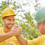 Two workers in hardhats shake hands -- department of labor news