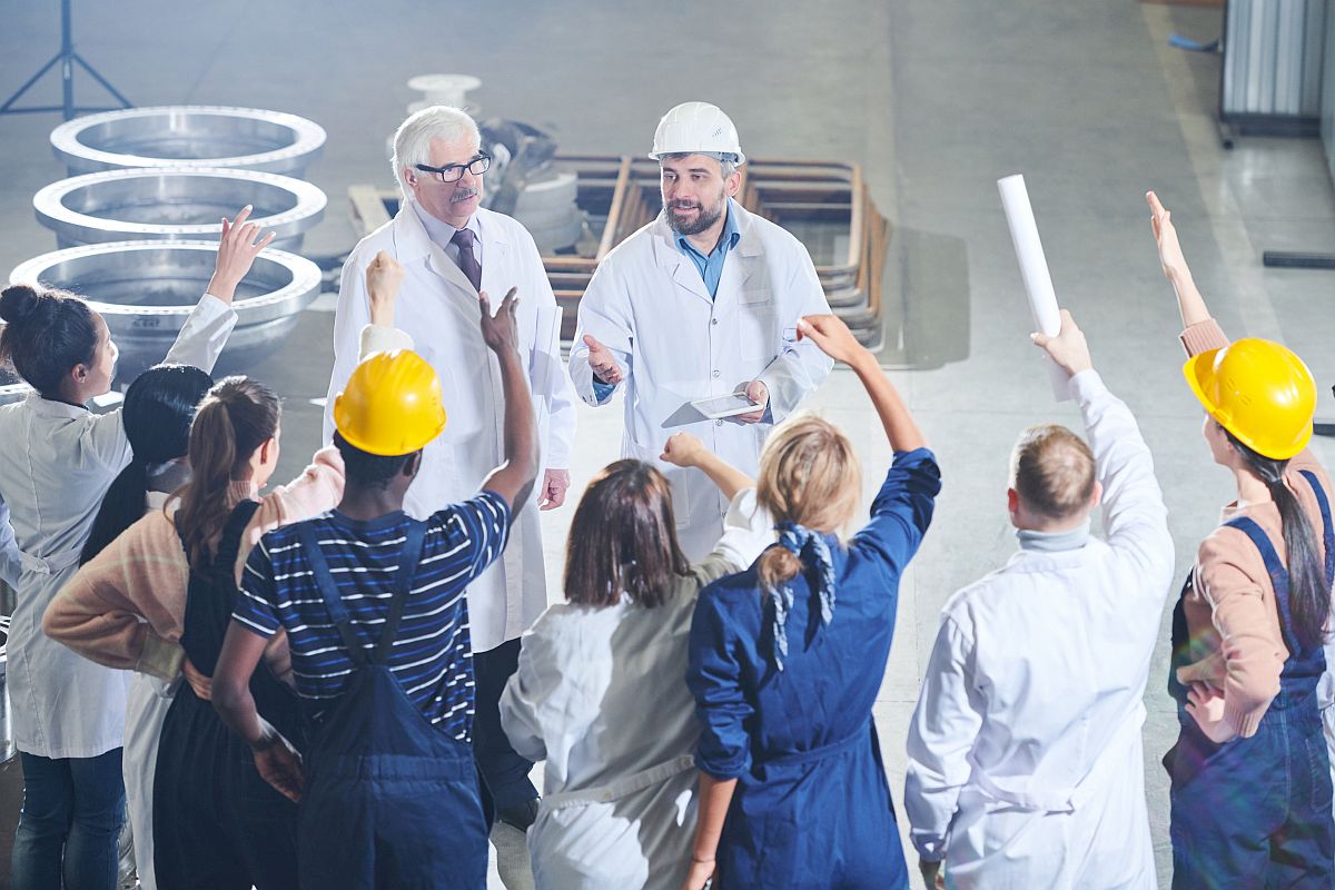 High angle portrait of angry factory workers yelling at business people in management; Jennifer Abruzzo initiatives at the NLRB concept