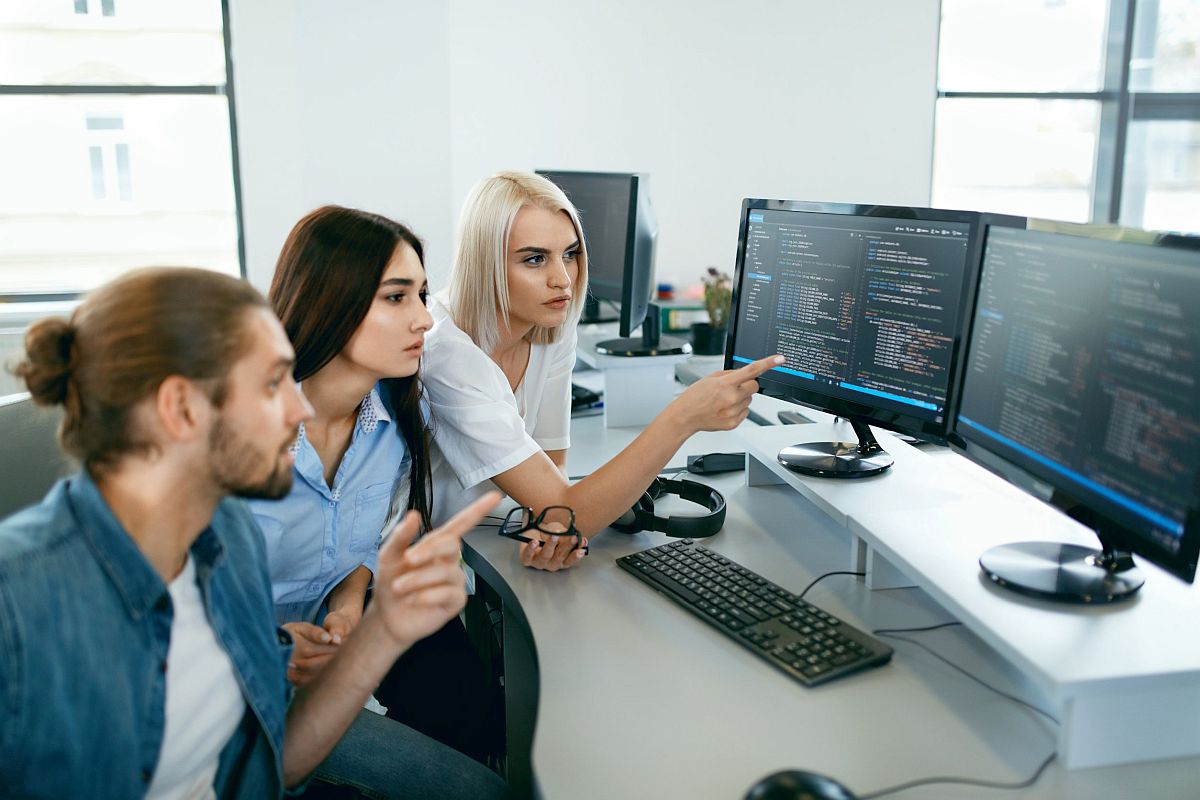 Three young people working together in front of computer screens; concept next generation of workers