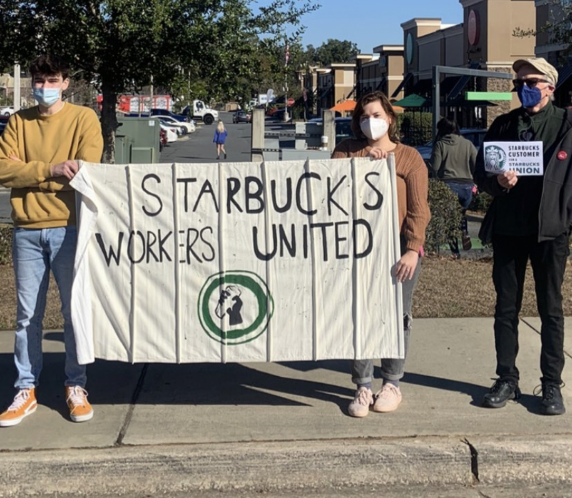 two workers hold a Starbucks Workers United flag