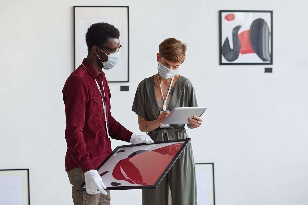 Two workers in art gallery examine pictures; white-collar workers concept