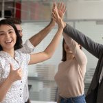 Group of happy people in office setting high-fiving each other; union victories concept
