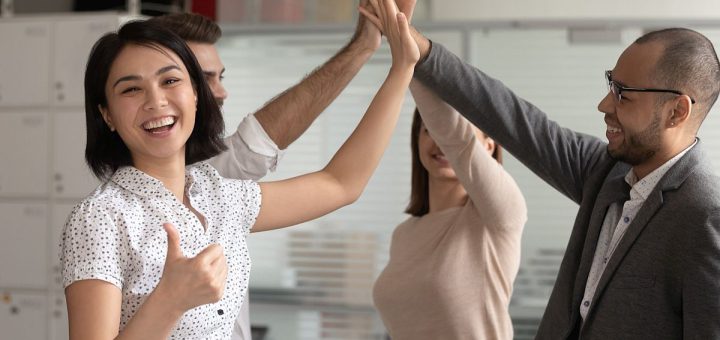 Group of happy people in office setting high-fiving each other; union victories concept