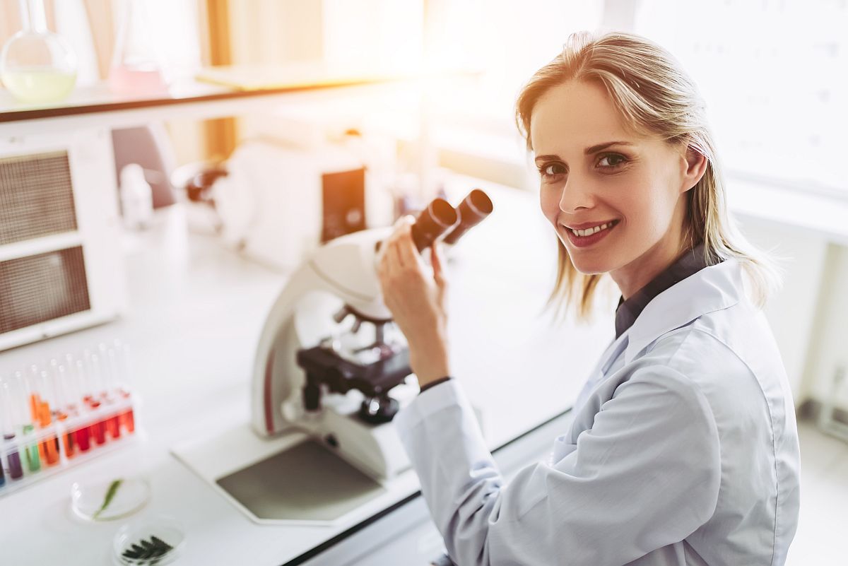 Woman in lab coat working in laboratory, using microscope; union victories concept.