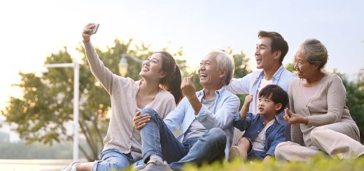 Three generations of a happy family sitting outdoors, taking a selfie; family benefits concept