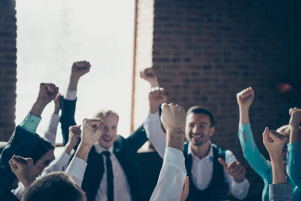 Group of professionals celebrating, with fists in the air; union dues concept