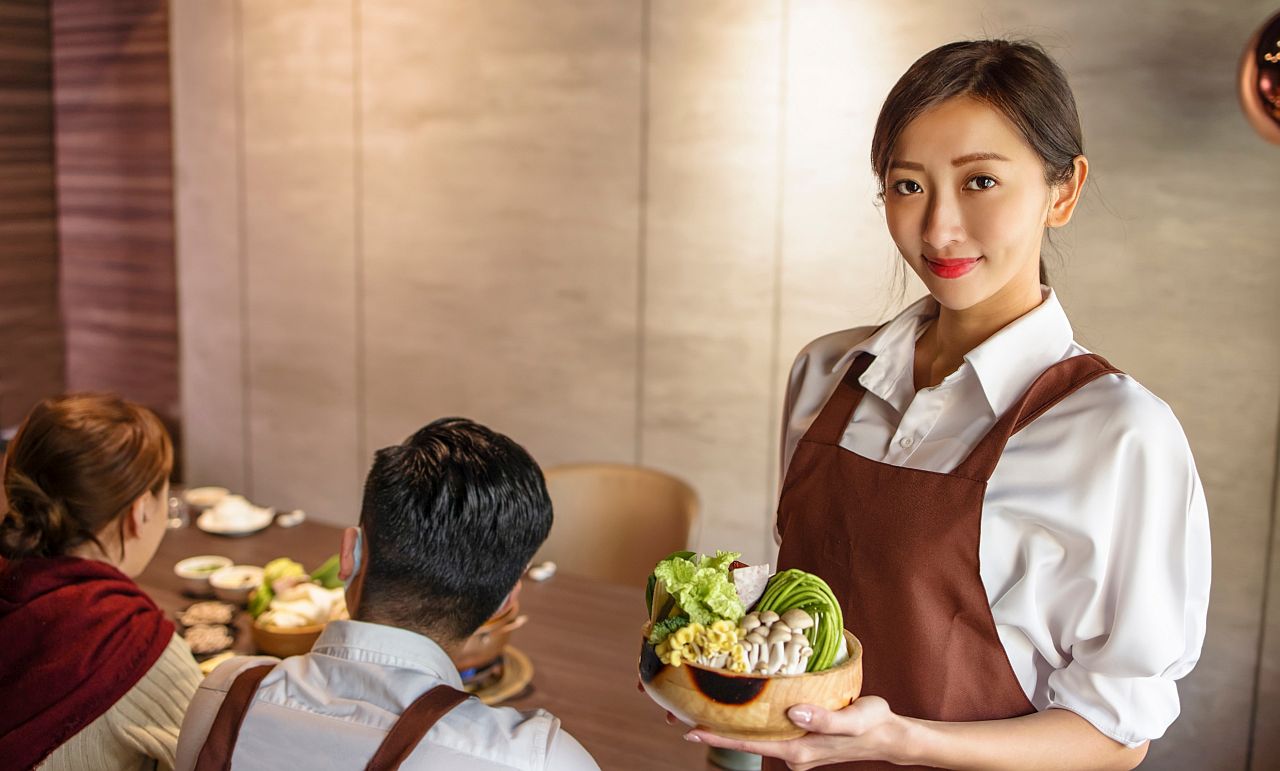 waiter bring vegetables for hot pot and serving customer in restaurant