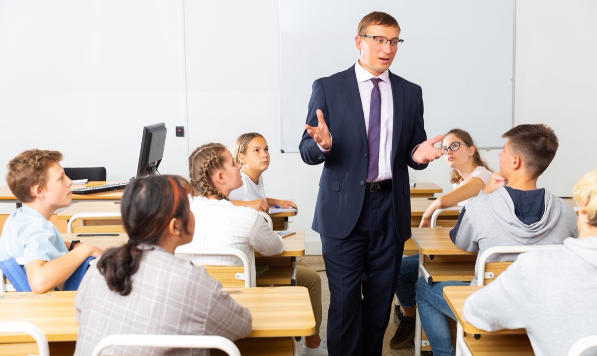 person in business suit chats with students in classroom; union high school students concept