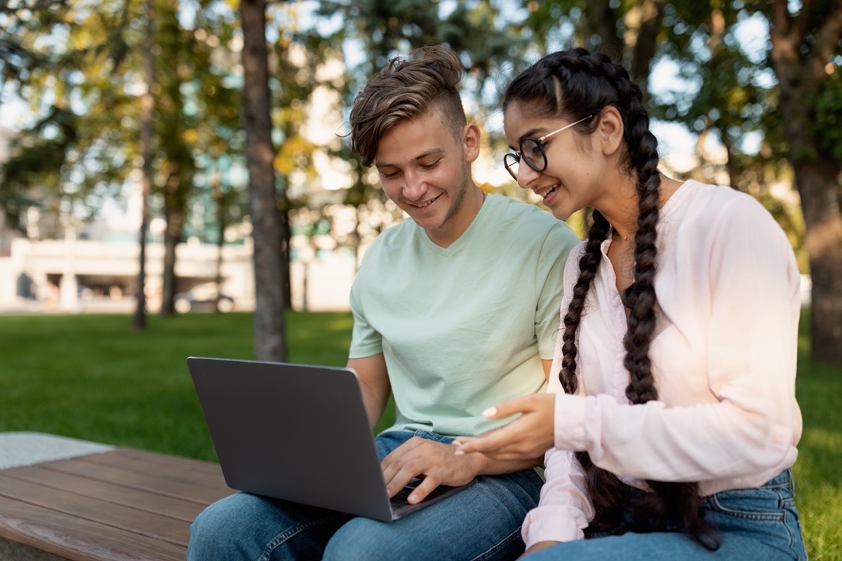 Two students share a laptop outdoors; union high school students concept