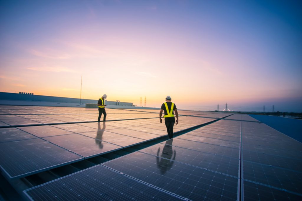 Technicians inspect and repair solar cells on the roof of building; inflation reduction act benefits unions concept