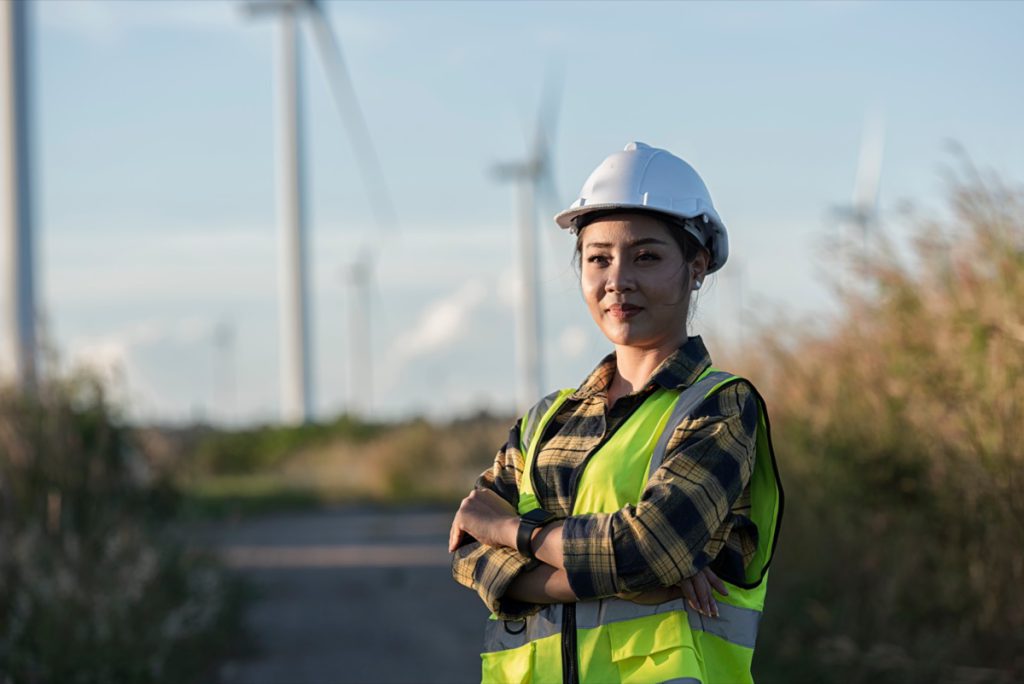 Woman in white helmet working at renewable energy farm; Inflation Reduction Act benefits concept