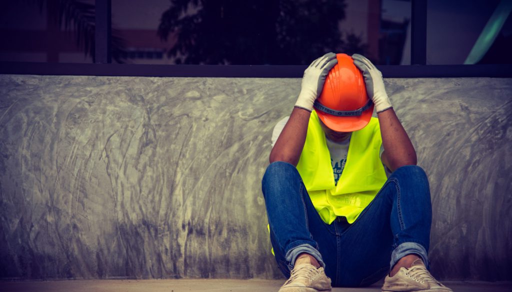 Construction worker sitting head in hands; right to work myth concept