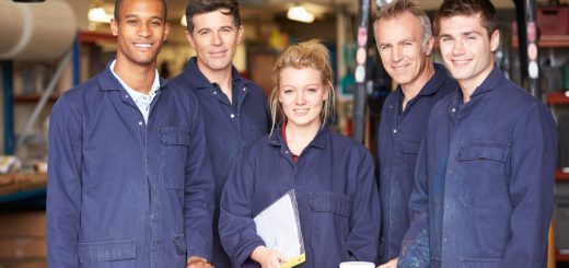 Group of smiling workers in plant; labor shortage in manufacturing industry concept
