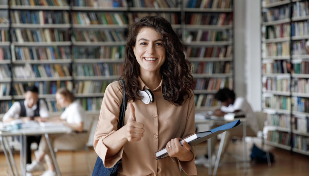 Smiling graduate student in library; Mid-2023-Worker-Wins concept