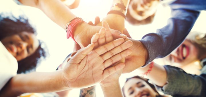 Young people stacking hands indicating solidarity; student workers forming unions concept